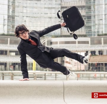 Business man with suitcase jumping over urban obstacles
